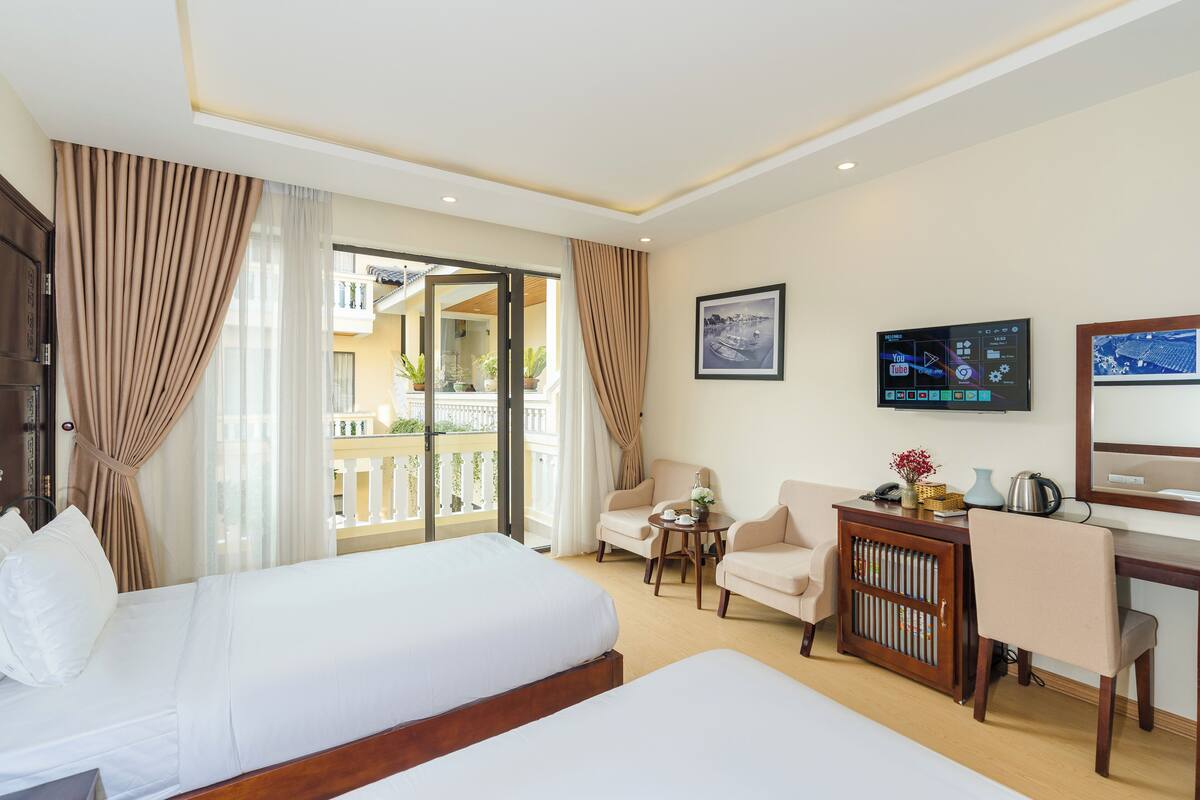 A hotel room with a bed, two armchairs, a desk, and a TV.