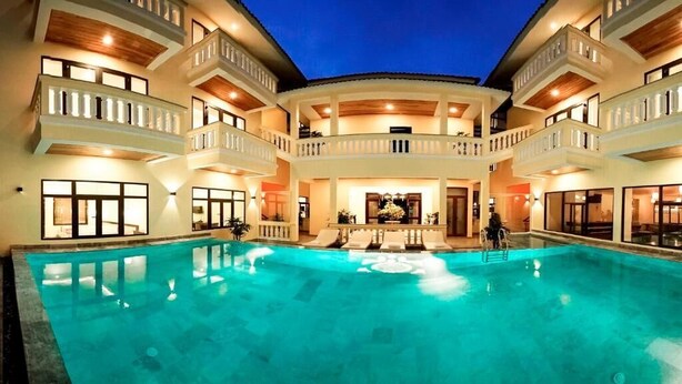 Una amplia piscina cubierta con varios balcones, un área de descanso central y una fachada bien iluminada.