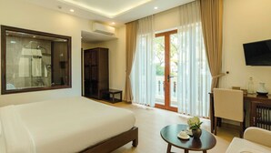 Habitación de hotel con una cama grande, un escritorio con silla, televisión y vistas al exterior a través de la ventana.