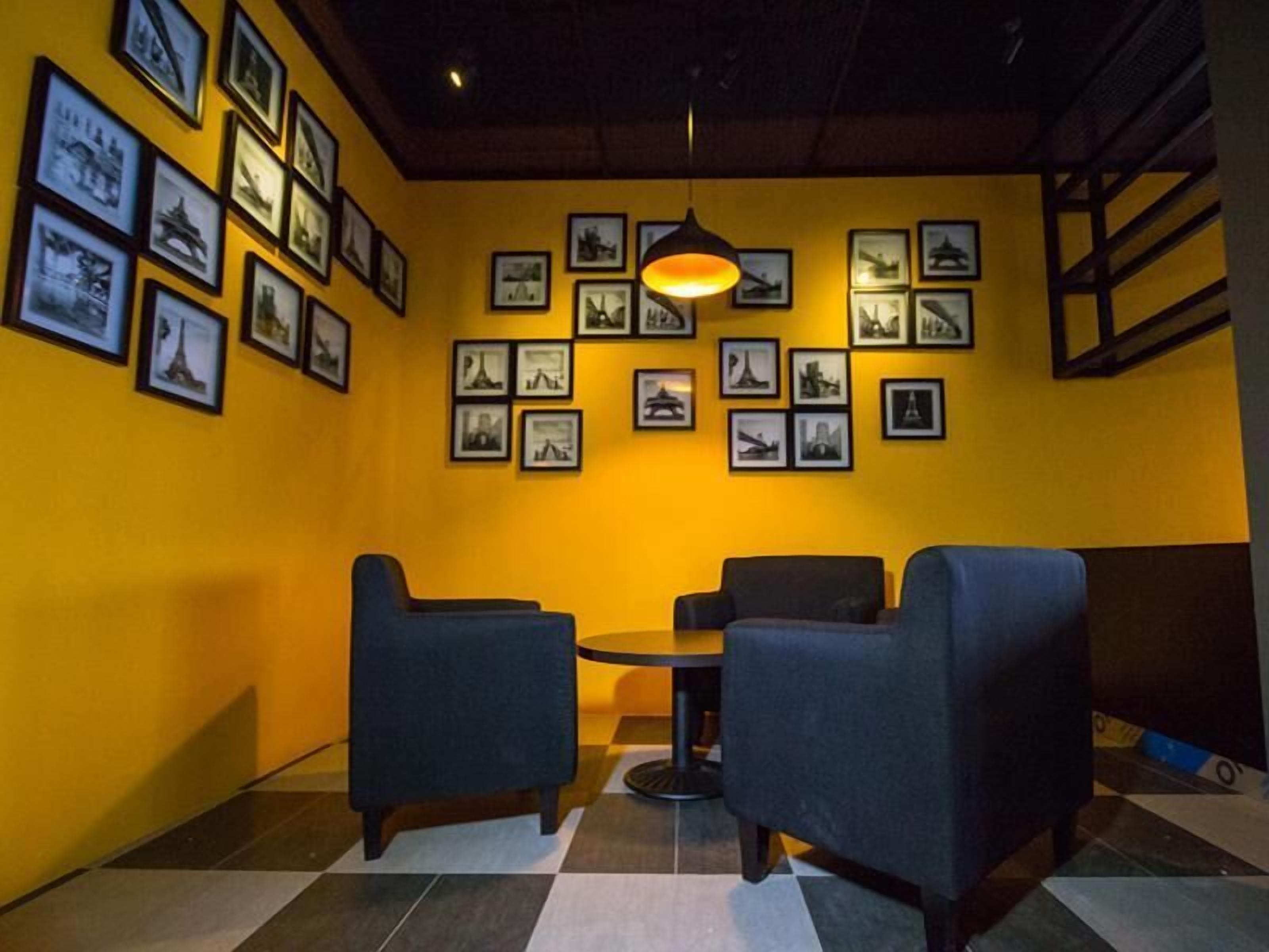 A room with a checkered floor, two chairs, a table, and a wall adorned with framed pictures.