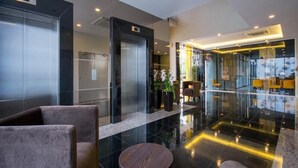 A modern lobby with a glass partition, a reception desk, and seating areas. - OMG Hotel (Simpang Ampat)