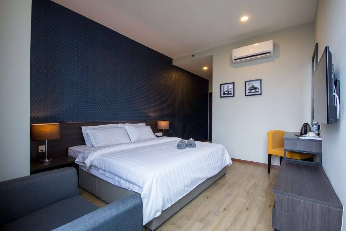 A modern hotel room with a large bed, a desk, and a chair.
