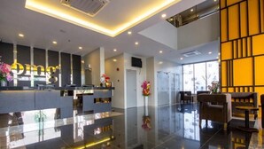 A modern hotel lobby with a reception desk, seating area, and large windows. - OMG Hotel (Simpang Ampat)