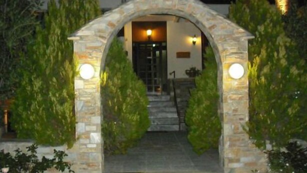 Un arco de piedra que da acceso a la entrada de un edificio, rodeado de vegetación.