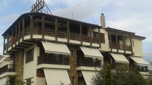 Un edificio de varios pisos con balcones y toldos, que destaca por su fachada de piedra y una chimenea.