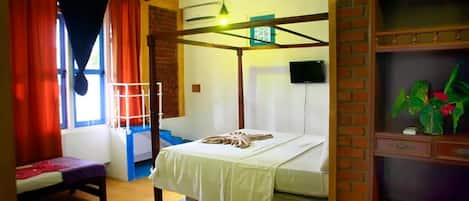 A room with a bunk bed, a desk, a chair, a TV, and a plant.
