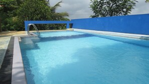 Una piscina con pared azul y escalera de metal.