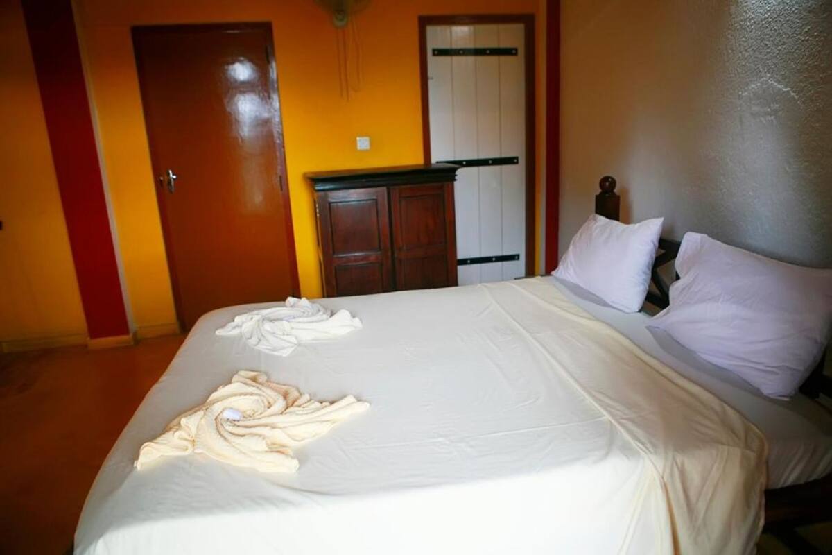 A hotel room with a bed, a wardrobe, and a door.