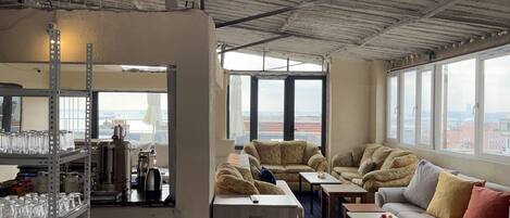 Una habitación con techo alto, ventanas amplias, kitchenette y zona de estar con vistas.