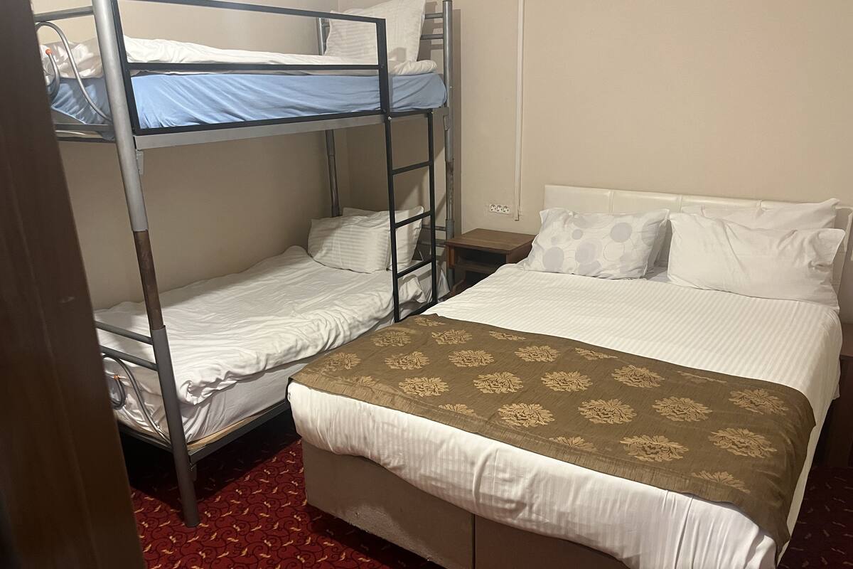 A room with bunk beds, a single bed, and a patterned carpet.
