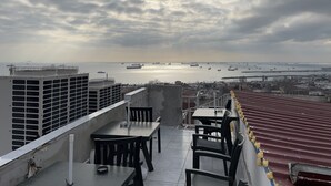 A rooftop terrace with tables and chairs, overlooking a harbor with boats and ships. - Istanbul Paris Hotel & Hostel (Istanbul)