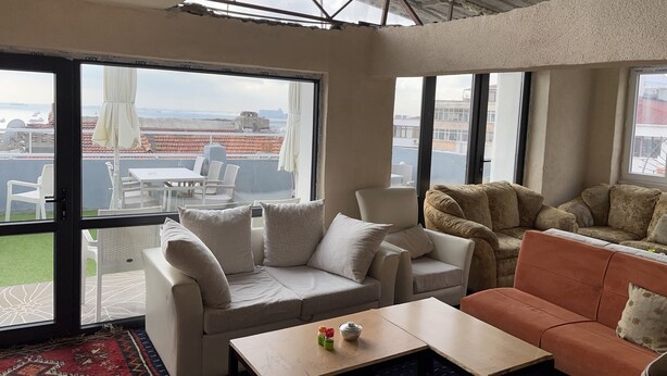 A spacious living area with a large window, a sofa, a coffee table, and a patterned rug. - Istanbul Paris Hotel & Hostel (Istanbul)