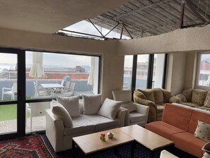 A spacious living area with a large window, a sofa, a coffee table, and a patterned rug. - Istanbul Paris Hotel & Hostel (Istanbul)