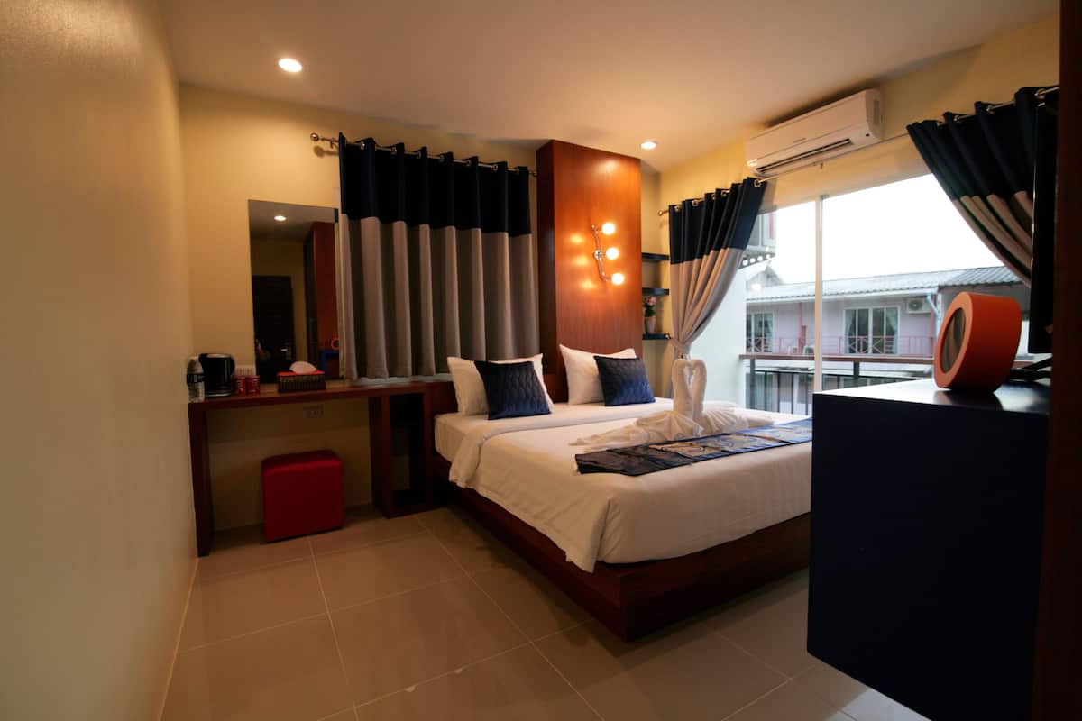 A modern hotel room with a large bed, a desk, and a view of the outside.