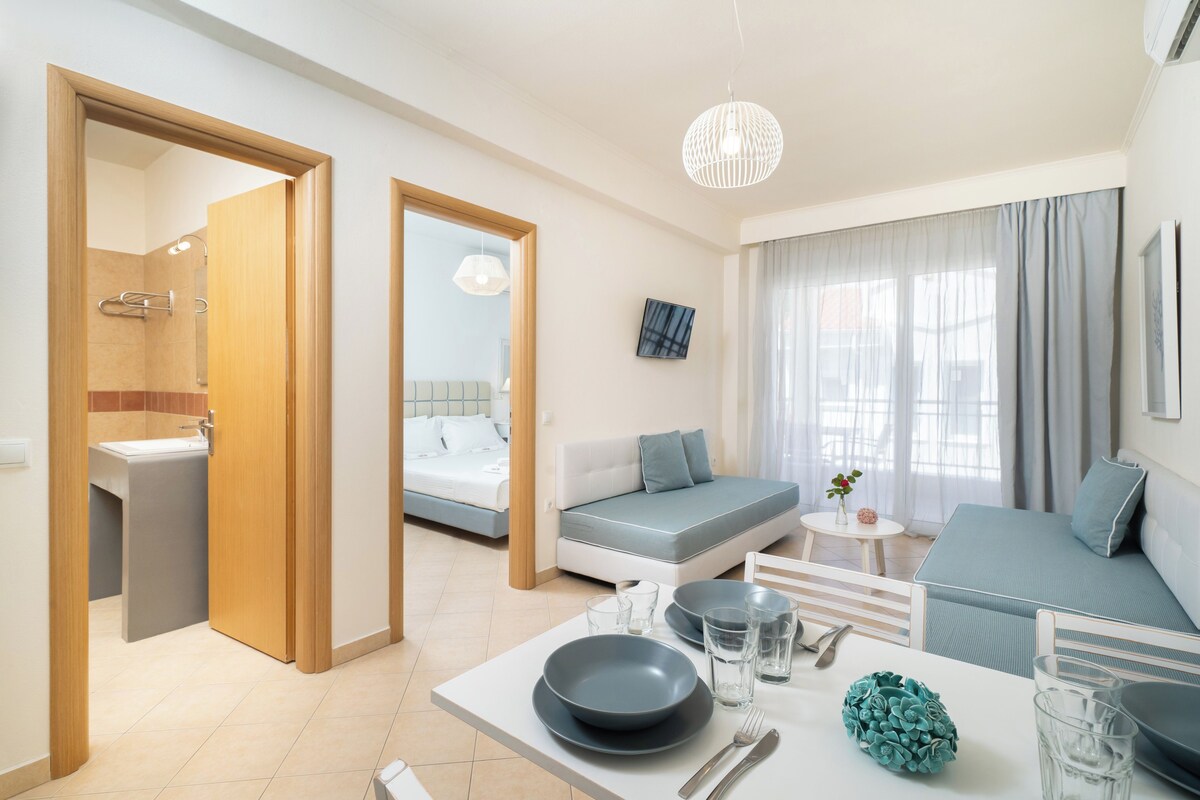 A modern hotel room with a dining area, a bed, and a bathroom.