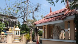 A building with a tiled roof, a statue, and a gated entrance.