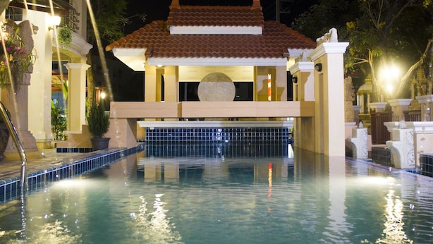 A swimming pool with a tiled roof structure in the center, surrounded by a poolside area with a tiled edge.