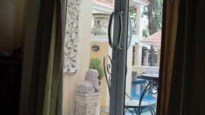 A room with a sliding glass door leading to an outdoor area with a pool and a tiled patio.