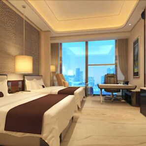 A hotel room with a large bed, a desk, and a view of the city.