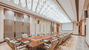 A conference room with a long table, multiple chairs, and a projector screen. - Wuhan You Yi International Hotel (Wuhan)