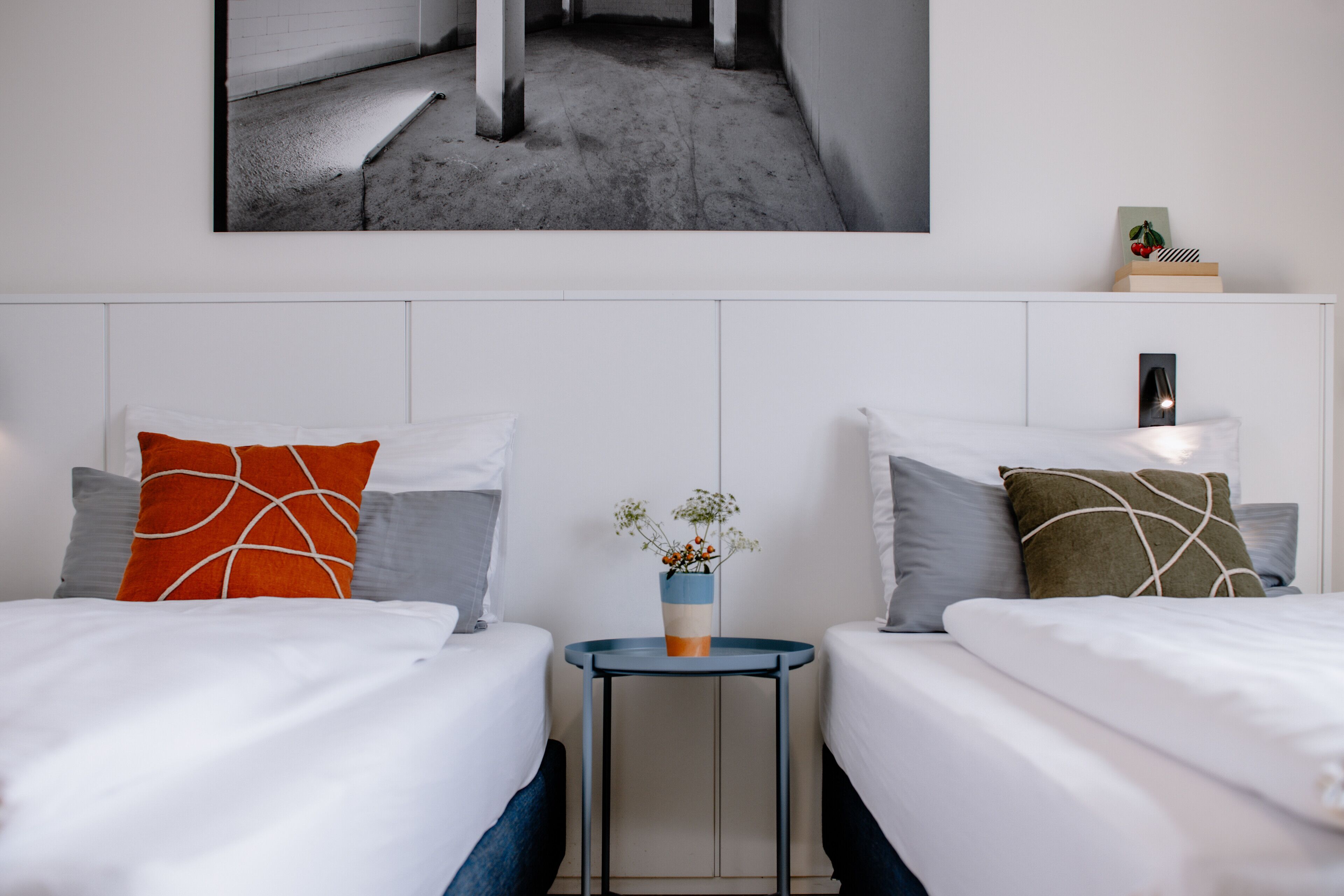 Ein Hotelzimmer mit zwei Betten, einem kleinen Tisch und einem Wandbild.