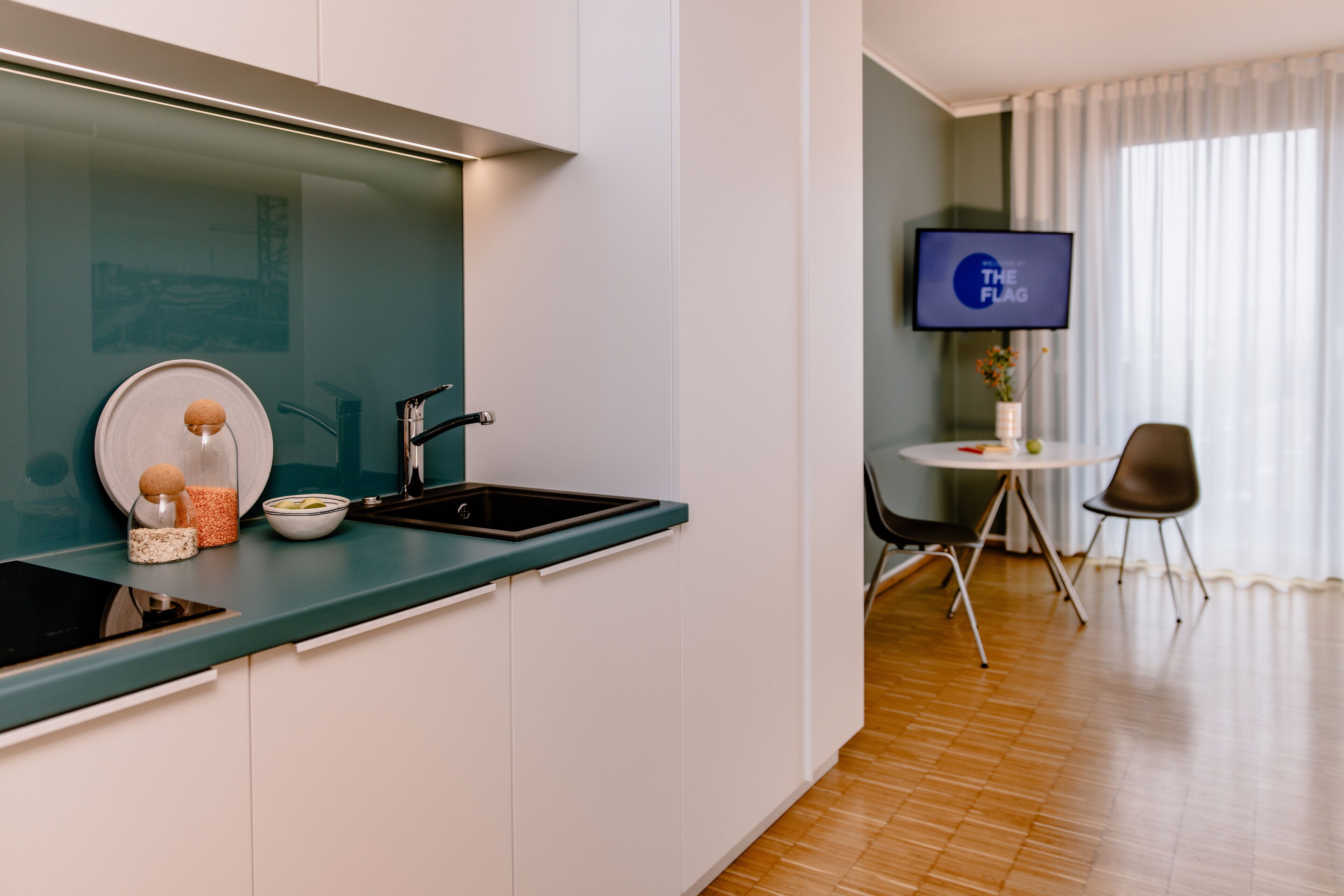 A modern kitchen with a built-in stove, a sink, and a dining area with a table and chairs.