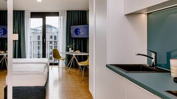 Ein Hotelzimmer mit einem Bett, einem Schreibtisch, einem Stuhl, einem Waschbecken und einem Fernseher.