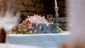 Una mesa con mantel blanco, una vela y flores decorativas.