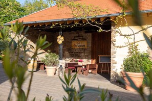 Un espacio de estar al aire libre rústico, con paredes de piedra, muebles de madera y plantas en macetas.