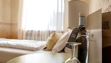 A hotel room with a bed, a bedside table with a bottle and a glass, and a QR code on a card.