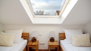 Un dormitorio con dos camas, un tragaluz y vistas a árboles.