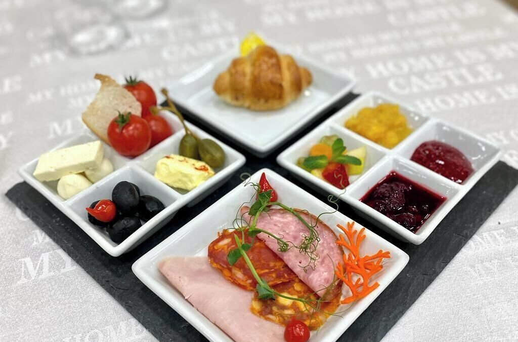 A mini buffet with various food items including cheese, olives, tomatoes, and a croissant.