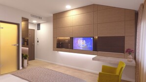 A modern hotel room with a large bed, a yellow chair, a TV mounted on the wall, and a small plant. - Hotel Vila Class (Satu Mare)