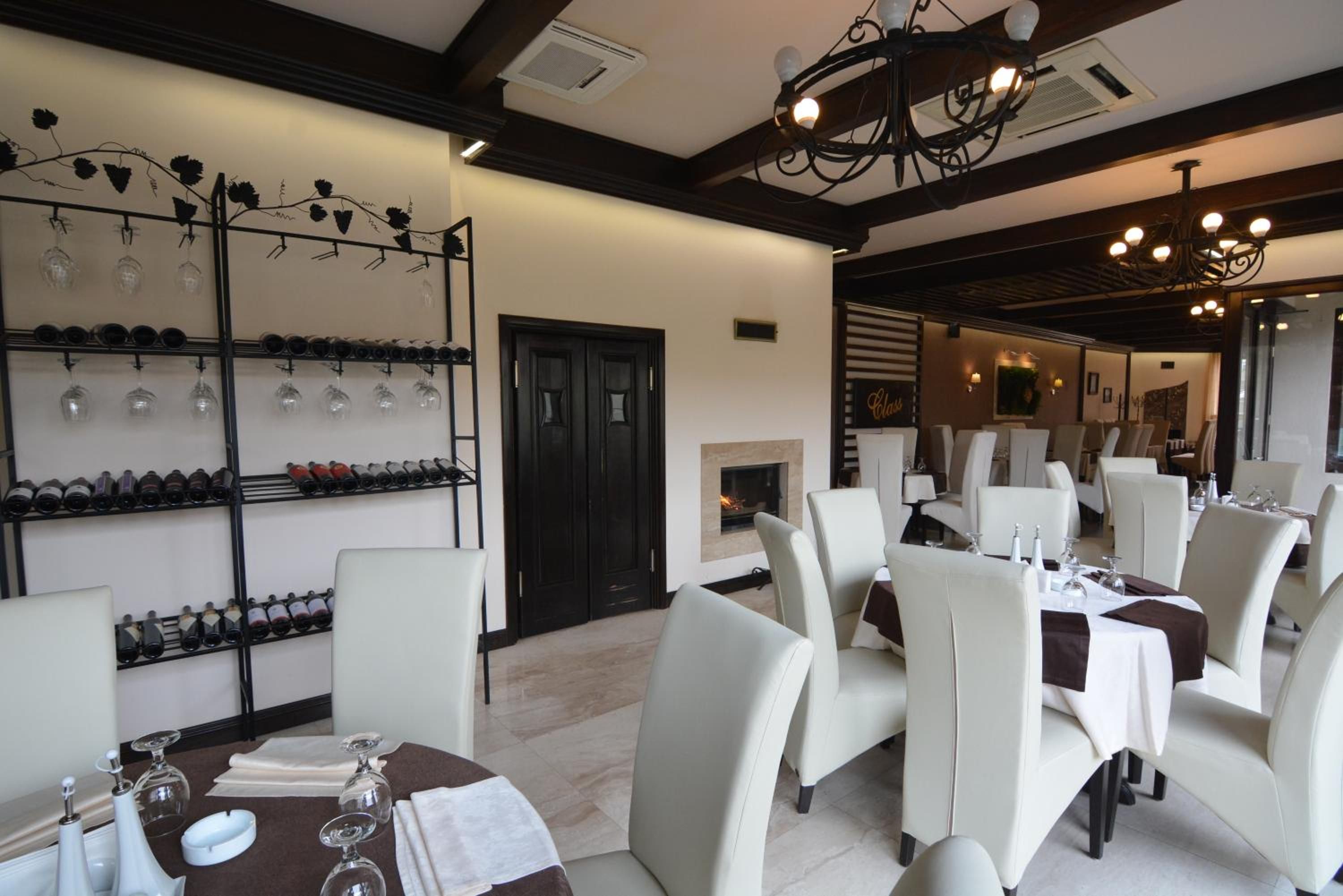 A restaurant interior with a wine rack, dining tables, and chairs.