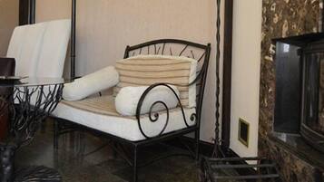 Ein gemütliches Zimmer mit Kamin, einem gepolsterten Sessel und einem kleinen Tisch mit Glasplatte.