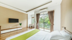 Una habitación de hotel moderna con una cama grande, un televisor de pantalla plana montado en la pared, una mesita y una ventana con cortinas.