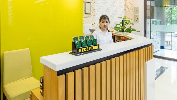 Un mostrador de recepción con un letrero amarillo brillante para HANA Serviced Apartment.