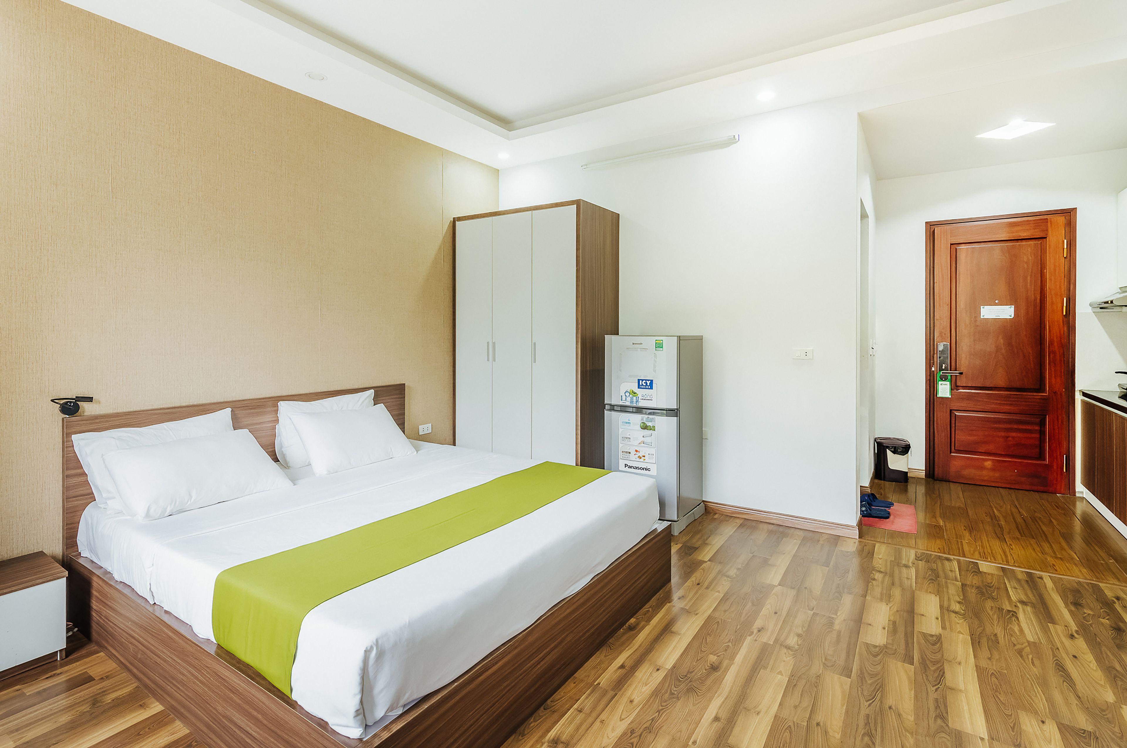 Habitación de hotel con cama, armario y pequeña zona de kitchenette.