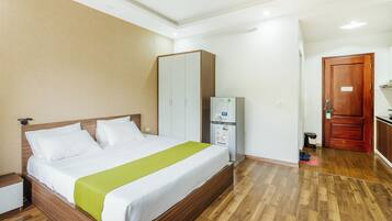 Habitación de hotel con cama, armario y pequeña zona de kitchenette.