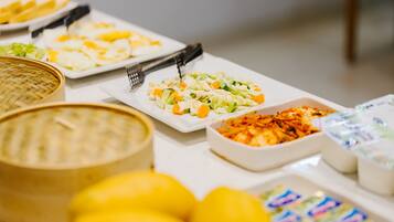 A buffet table with various dishes, including a bowl of soup, a plate of salad, and several containers of dips.