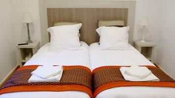 A twin room with two beds, each with a headboard, bedside tables, lamps, and patterned bedspreads.