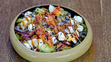 A bowl of salad with various ingredients and a drizzle of dressing.
