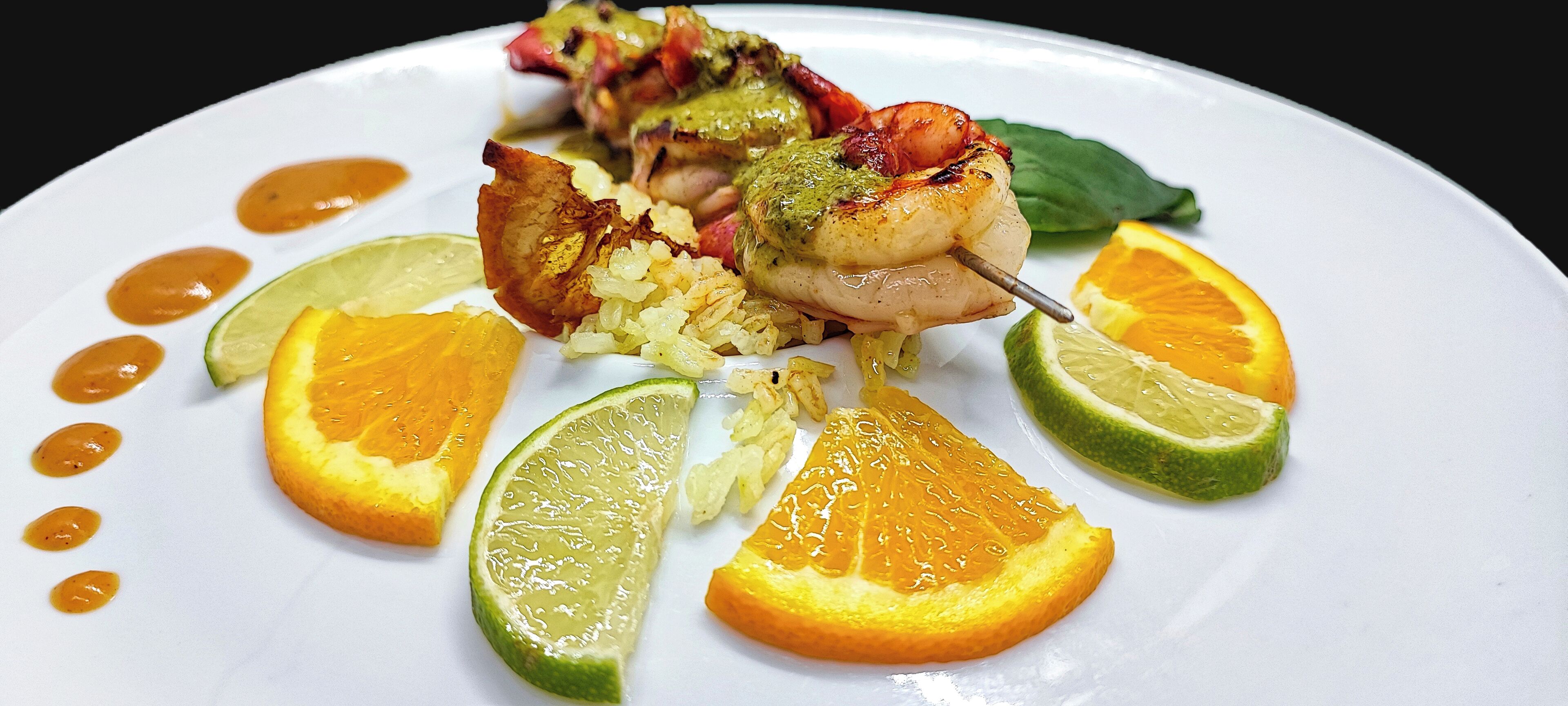 Une assiette contenant du poulet grillé, du riz et des tranches de citron vert.