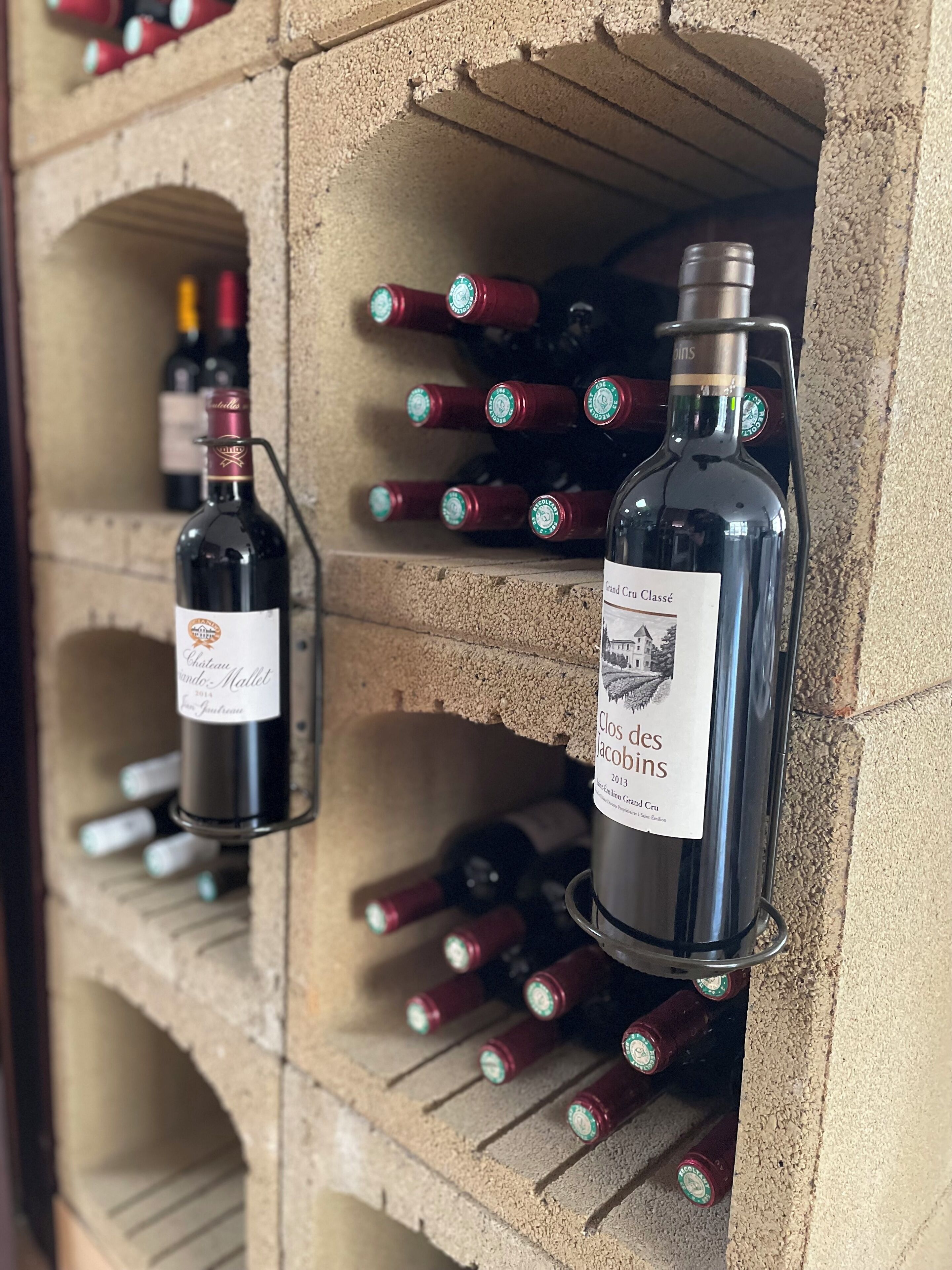 A wine rack with bottles of wine, including a bottle labeled "Clos des Jacobins 2013."