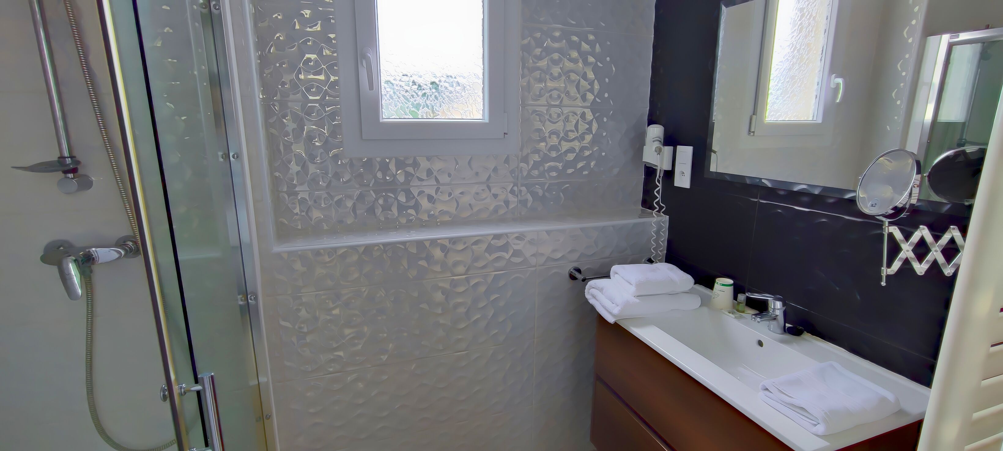 A bathroom with a glass shower enclosure, a sink with a mirror, and a towel rack.