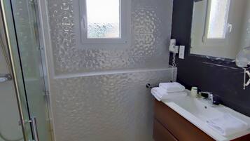 A bathroom with a glass shower enclosure, a sink with a mirror, and a towel rack.