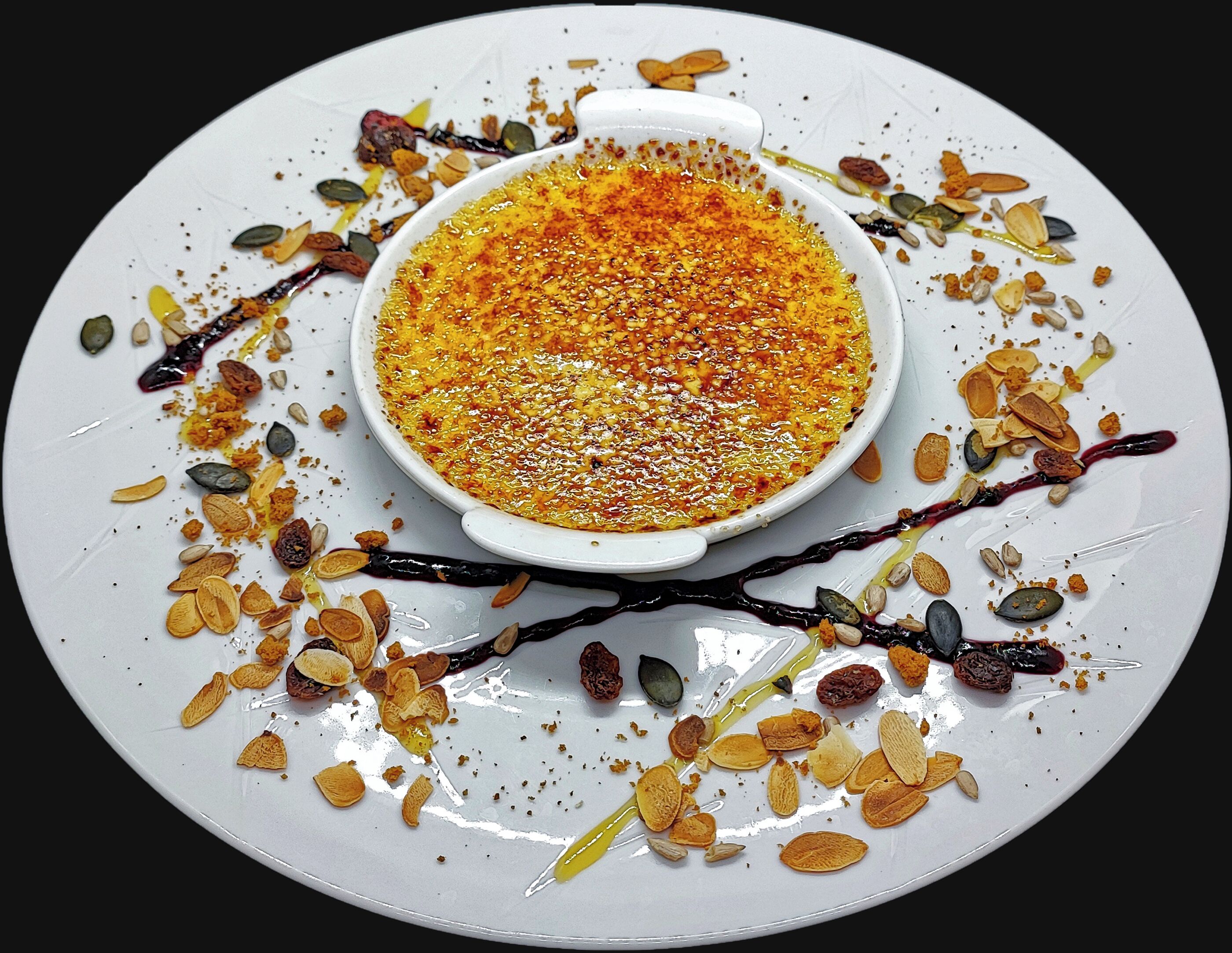 A dessert dish with a creamy topping, surrounded by various nuts and seeds on a white plate.