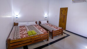 A room with two wooden beds, each with patterned bedding and pillows, and a wooden wardrobe.