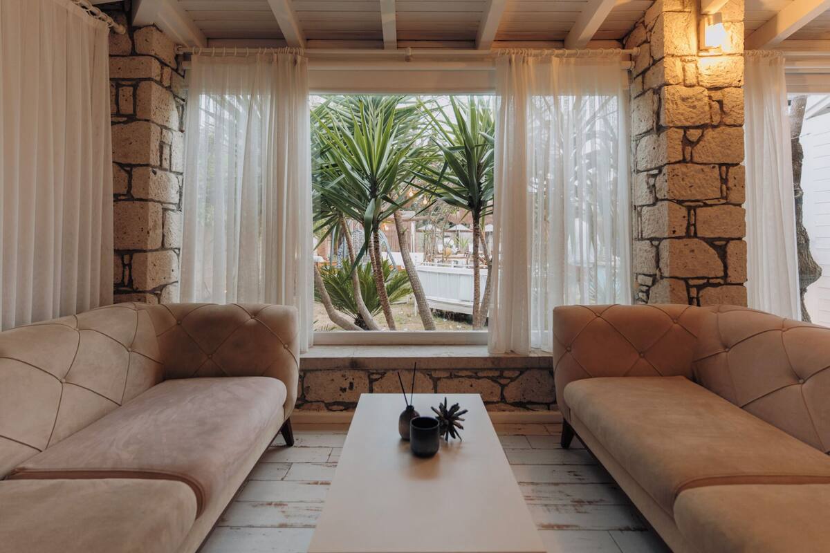 A cozy room with two beige sofas, a white coffee table, and a stone wall.