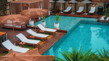 Una piscina al aire libre, sombrillas, tumbonas